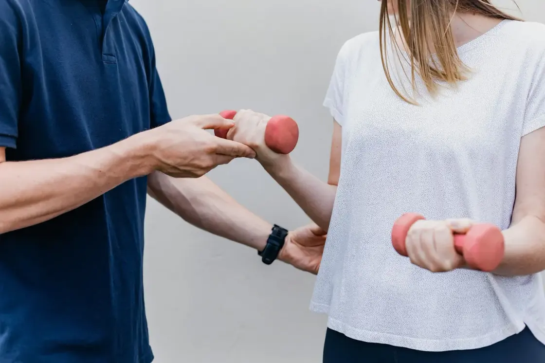 Physiotherapist guiding a patient through a dumbbell strengthening exercise